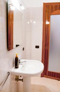 La salle de bains est pourvue d'un lavabo blanc et d'un miroir. dans l'établissement MAISON SAN MARTINO, à Naples