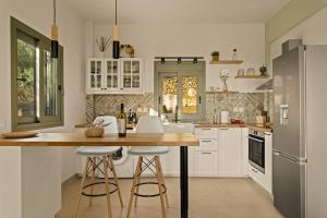 a kitchen with white cabinets and a island with bar stools at Casa Mainotti - Villa in Mani in Nomitsís