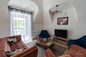 ein Wohnzimmer mit einem Sofa, Stühlen und einem TV in der Unterkunft Le Manoir, appartement Beryl in Le Bourg-dʼOisans