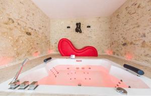 a bath tub in a room with a red chair at L'indiscrete Love Room - Hammam-Sauna-SPA in Saint-Cyr-sur-Loire