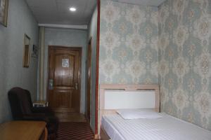 a bedroom with a bed and a chair and a door at City Hostel & Tours in Ulaanbaatar