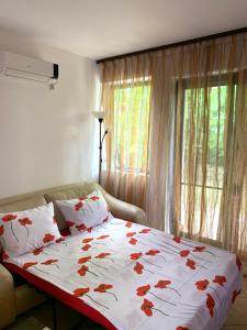 a bedroom with a bed with red flowers on it at Апартамент Silver Star in Sozopol
