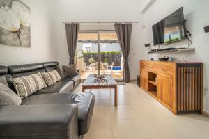 sala de estar con sofá de cuero negro y TV en Villa with Private Pool - LO4LT, en Torre-Pacheco