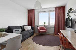 un soggiorno con divano e sedia rossa di Forenom Aparthotel Stockholm Alvik a Stoccolma