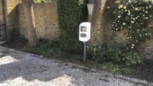 een witte parkeermeter naast een bakstenen muur bij Bed & Breakfast Ohé en Laak in Ohé en Laak