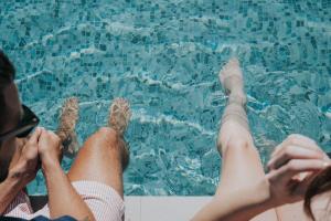 依拉佩特拉的住宿－Pignolia Suites - Adults Only，坐在游泳池旁的男人和女人
