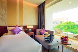 a hotel room with a bed and a chair and a window at Seashells Phu Quoc Hotel & Spa in Phu Quoc