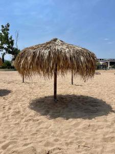 a large straw umbrella on a sandy beach at Апартамент в комплекс Свети Никола плаж Градина in Chernomorets