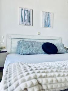 a bedroom with a white bed with blue pillows at Апартамент в комплекс Свети Никола плаж Градина in Chernomorets