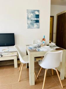 チェルノモレツにあるАпартамент в комплекс Свети Никола плаж Градинаのダイニングルーム(木製テーブル、白い椅子付)