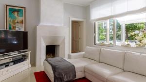 a living room with a white couch and a fireplace at Villa Guidi 10 Emma Villas in Milano Marittima