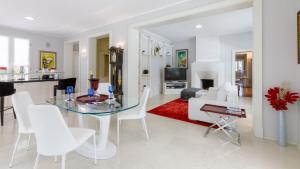 ein Wohnzimmer mit einem Glastisch und weißen Stühlen in der Unterkunft Villa Guidi 10 Emma Villas in Milano Marittima