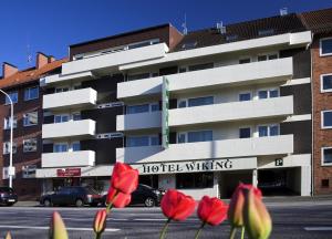 ein Hotelgebäude mit roten Blumen davor in der Unterkunft Hotel Wiking in Kiel