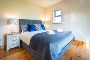 a bedroom with a bed with blue sheets and a window at Dingle View - 37 Tír Na Fiuise in Dingle
