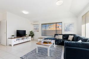 a living room with a blue couch and a table at Avalon Beach Escape ~ Family Favourite with Wifi in Mandurah