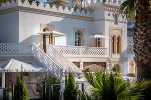 a large white house with white stairs and umbrellas at La Villa Mauresque in Saint-Raphaël