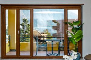 una porta in vetro con tavolo e sedie sul balcone di Casa Melide Seeblick a Melide