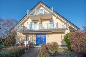 a house with a blue door and a balcony at Ostseeblick Apartmenthaus im Ostseebad Nienhagen in Ostseebad Nienhagen