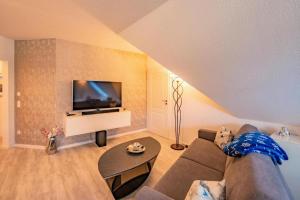 a living room with a couch and a flat screen tv at Ostseeblick Apartmenthaus im Ostseebad Nienhagen in Ostseebad Nienhagen