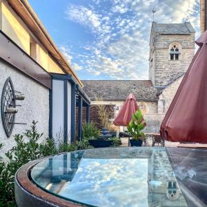 a courtyard with a swimming pool and a church at Auberge du Cheval Blanc Logis in Chamouilley