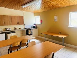 a kitchen with wooden tables and chairs in a room at Greenway & Copper Coast Hostel in Bunmahon