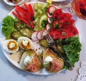 une assiette de denrées alimentaires contenant des œufs et des légumes sur une table dans l'établissement Pensjonat Willa w Parku, à Polanica-Zdrój