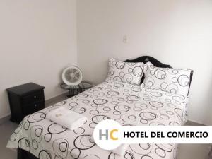 a bedroom with a bed with a black and white comforter at Hotel del Comercio in Villavicencio