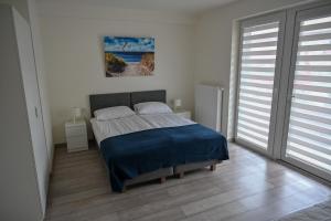 a bedroom with a bed and a painting on the wall at NORD HOUSE Apartamenty in Władysławowo