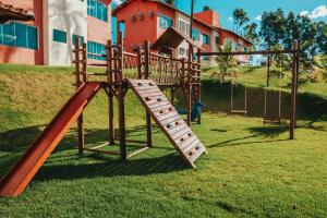 a wooden playground with a slide in the grass at Hotel Chalé Capitólio in Capitólio