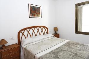 ein Schlafzimmer mit einem Bett, zwei Kommoden und einem Fenster in der Unterkunft AT250 Con piscina, parking, wifi, playa a 150m in Torredembarra