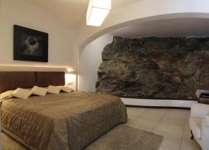 a bedroom with a bed and a large rock wall at Delina Mountain Resort in Anogeia