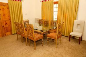 una sala da pranzo con tavolo in vetro e sedie di Skardu Orchard Guest House a Skardu