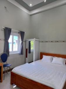 una camera con un grande letto e una sedia blu di Nhà nghỉ Mỹ Nhật - Đảo Phú Quý -Bình Thuận a Cu Lao Thu