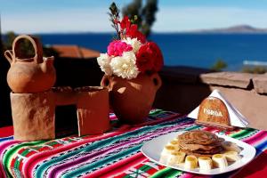 Hospedaje Rural La Florida en Llachon, Titicaca في بونو: طاولة مع طبق من الطعام وطبق من الفطائر
