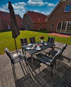 a table with chairs and an umbrella on a patio at Haifisch in Greetsiel