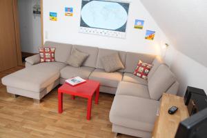 a living room with a couch and a red stool at Möwennest in Norddeich