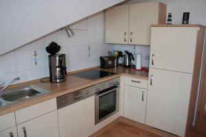 a kitchen with white cabinets and a sink at Möwennest in Norddeich