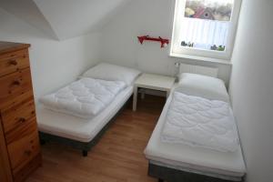 a room with two beds and a desk and a window at Möwennest in Norddeich
