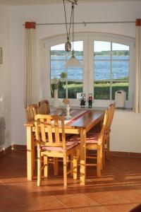 a dining room table with chairs and a large window at See in Sicht in Sternberg