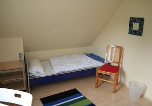 a small bedroom with a bed and a chair at See in Sicht in Sternberg