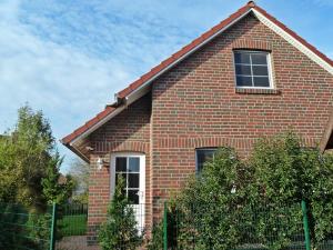 a red brick house with a fence in front of it at Deichbrise in Greetsiel