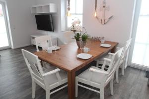 a dining room with a wooden table and white chairs at Ankerplatz in Greetsiel
