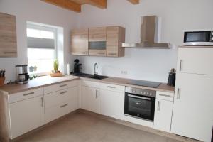 a kitchen with white cabinets and a white refrigerator at Bei Ruhe in Loppersum