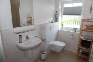 a white bathroom with a sink and a toilet at Bei Ruhe in Loppersum +26 photos