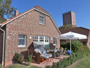 a brick house with a patio with a table and an umbrella at Achterhook in Norden