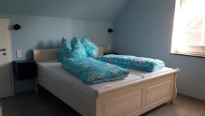 a bed with blue pillows on it in a room at Dat Hygge Huus in Greetsiel
