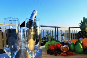 twee glazen wijn zittend op een tafel met fruit bij Coral Blue Bay Villa in Coral Bay