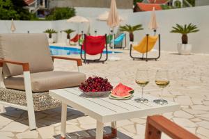 a table with two glasses of wine and a bowl of fruit at Georgiy Lux Apartments in Lastva