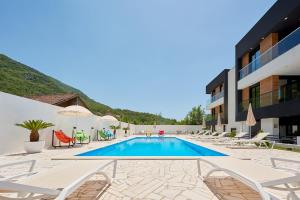 einen Pool mit Stühlen und Sonnenschirmen neben einem Gebäude in der Unterkunft Georgiy Lux Apartments in Lastva
