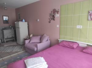 a bedroom with a pink bed and a couch at Chambre spatieuse avec grand lit. in Aspet